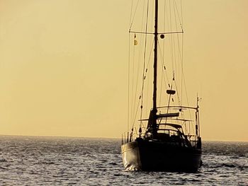 Boats sailing in sea at sunset