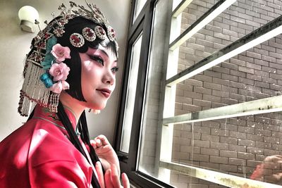 Side view of woman standing by window