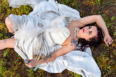 High angle view of woman laying in mud with wedding dress