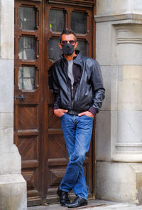 Young man wearing sunglasses standing against door