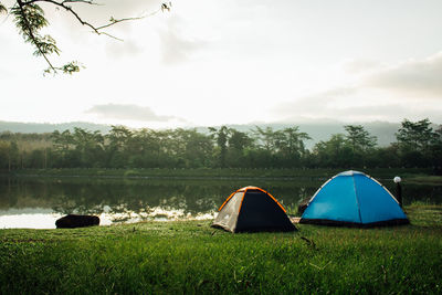 Scenic view of tent by lake against sky