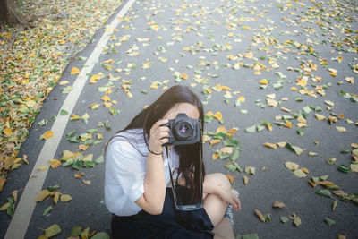 Portrait of woman photographing with autumn leaves