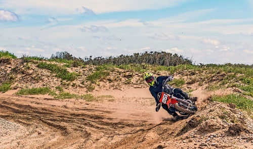 Person riding motorcycle on land against sky