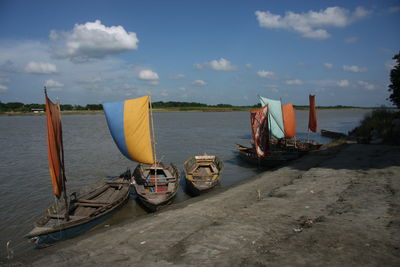 Sailboats moored on beach against sky