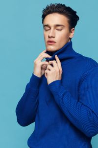 Young man with eyes closed against blue background