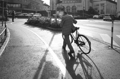 Rear view of man riding bicycle on city street