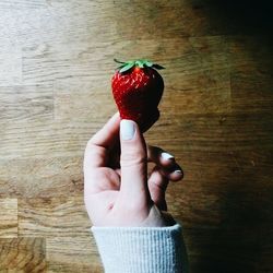 Cropped hand of woman holding strawberry on table