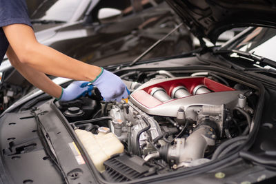 Midsection of mechanic repairing car in garage