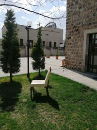 Empty bench in park by buildings