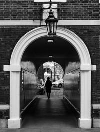 Rear view of person walking at archway in city