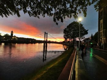 View of suspension bridge over river during sunset