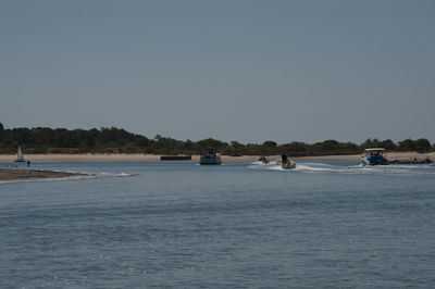 Boats sailing in sea against clear sky