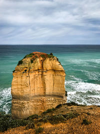 Rock formation by sea against sky