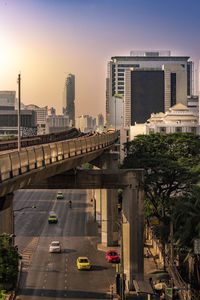 Traffic on road by buildings against sky in city