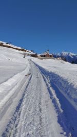 Snow covered landscape against clear blue sky