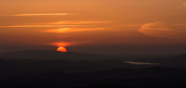 Scenic view of mountains against dramatic sky during sunset