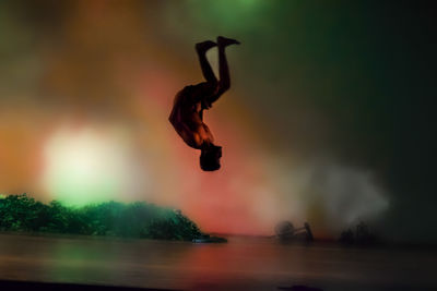 Low angle view of silhouette man jumping against sky during sunset