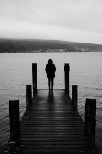 Silhouette woman standing on pier against lake