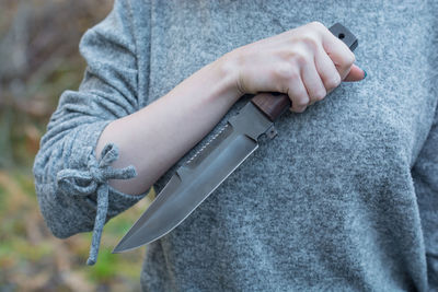 Midsection of woman holding knife while standing outdoors