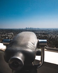 Close-up of coin-operated binoculars against cityscape