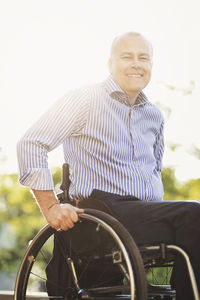 Portrait of happy man sitting in wheelchair outdoors