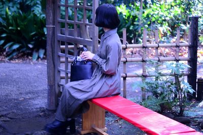 Side view of woman sitting on bench outdoors