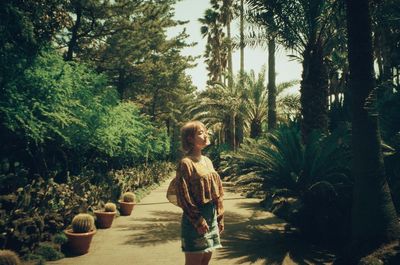 Young woman standing on footpath by trees