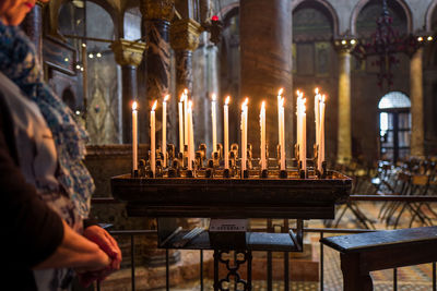 Midsection of woman standing by lit candles in church