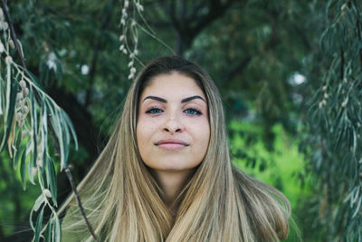 Portrait of young woman against trees