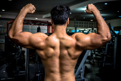 Rear view of shirtless man flexing muscles