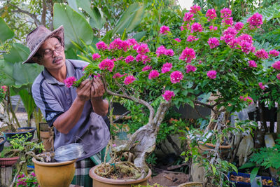 Full length of smiling young woman holding potted plant at yard