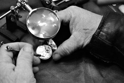 High angle view of cropped hands repairing pocket watch