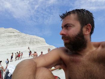 Midsection of shirtless man and woman against sky