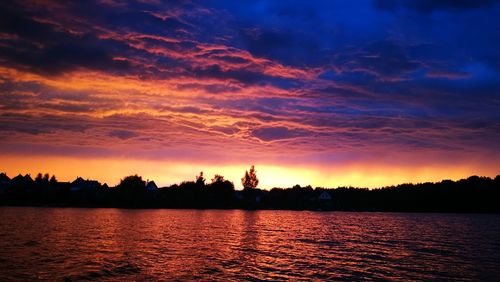 Silhouette trees by lake against sky during sunset