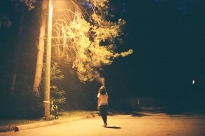 Woman standing on road against sky at night