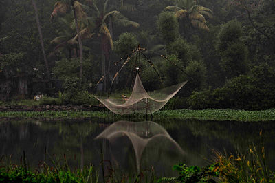 Traditional chinese fishing net over river against trees