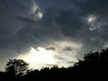 Silhouette of trees against cloudy sky