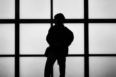 Rear view of silhouette woman standing against window