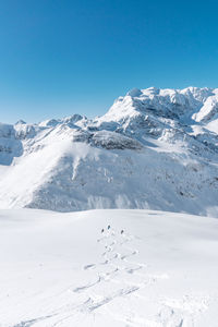 Scenic view of snow covered mountains against clear blue sky