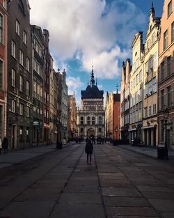 Street leading towards golden gate against sky in city