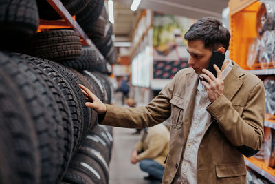 Man talking on phone choosing tire at shop