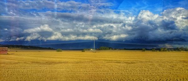 Scenic view of field against cloudy sky