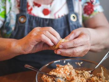 Hands of a senior woman wrapping a leaf of sauerkraut with rice-meat filling