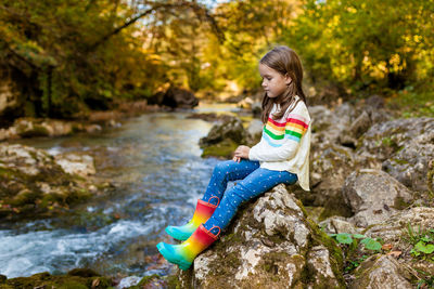 Girl sitting on rock by stream