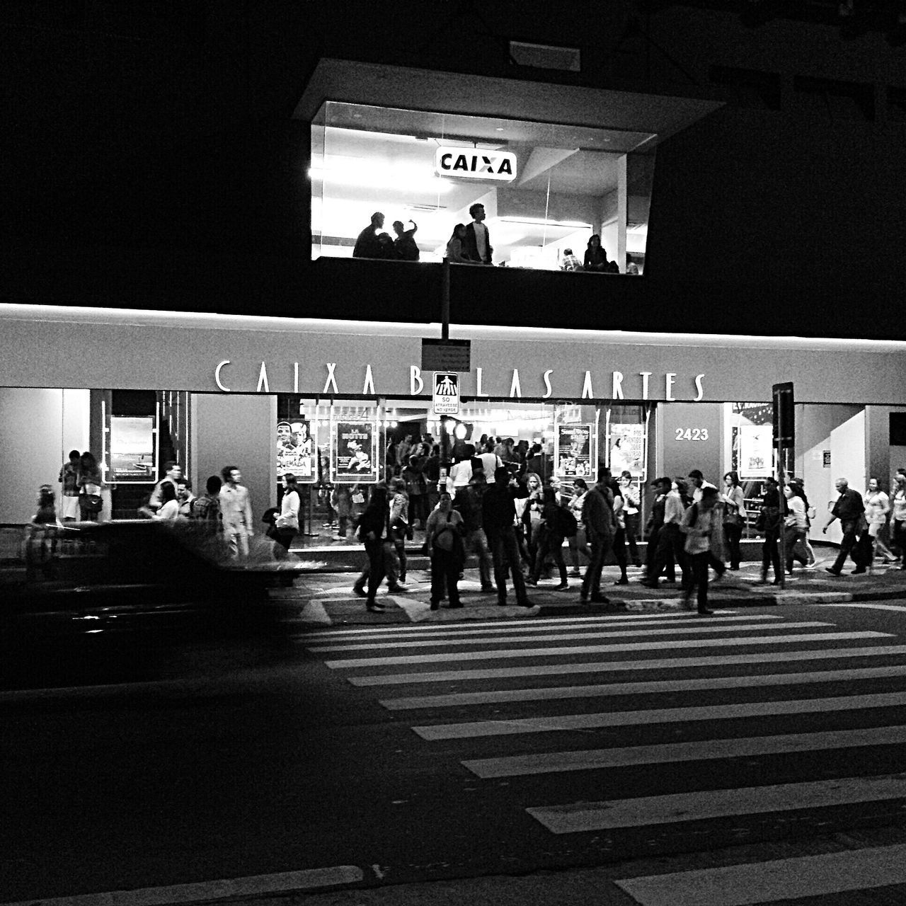 PEOPLE WALKING ON ILLUMINATED CITY AT NIGHT