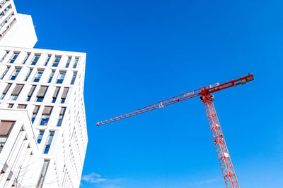 Low angle view of crane against clear blue sky