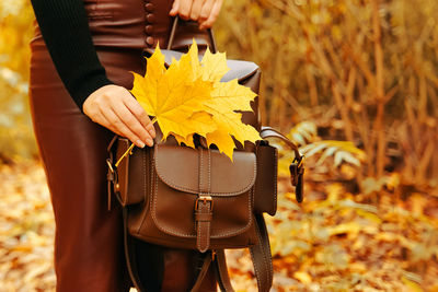 Midsection of woman holding yellow umbrella standing on field