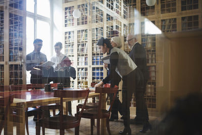 Male and female professionals standing in board room seen through glass