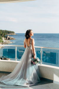 Full length of woman standing by sea against sky