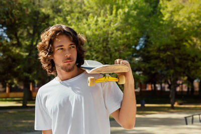 Portrait of young man standing against trees